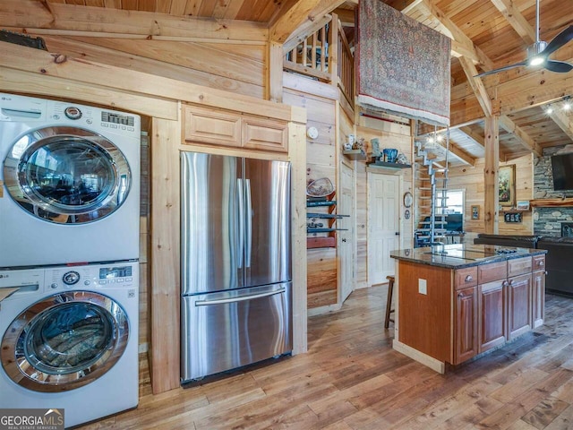 721 Dial Rd, Blue Ridge, GA 30513 - kitchen with freestanding refrigerator, wooden ceiling with exposed beams, stacked washer and clothes dryer, light wood-style flooring, and wood walls