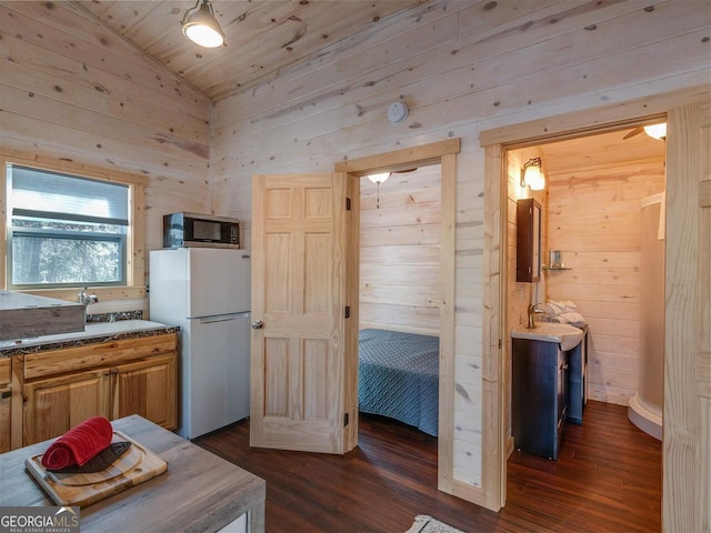 721 Dial Rd, Blue Ridge, GA 30513 - kitchen featuring freestanding refrigerator, stainless steel microwave, wooden walls, a sink, and dark wood finished floors