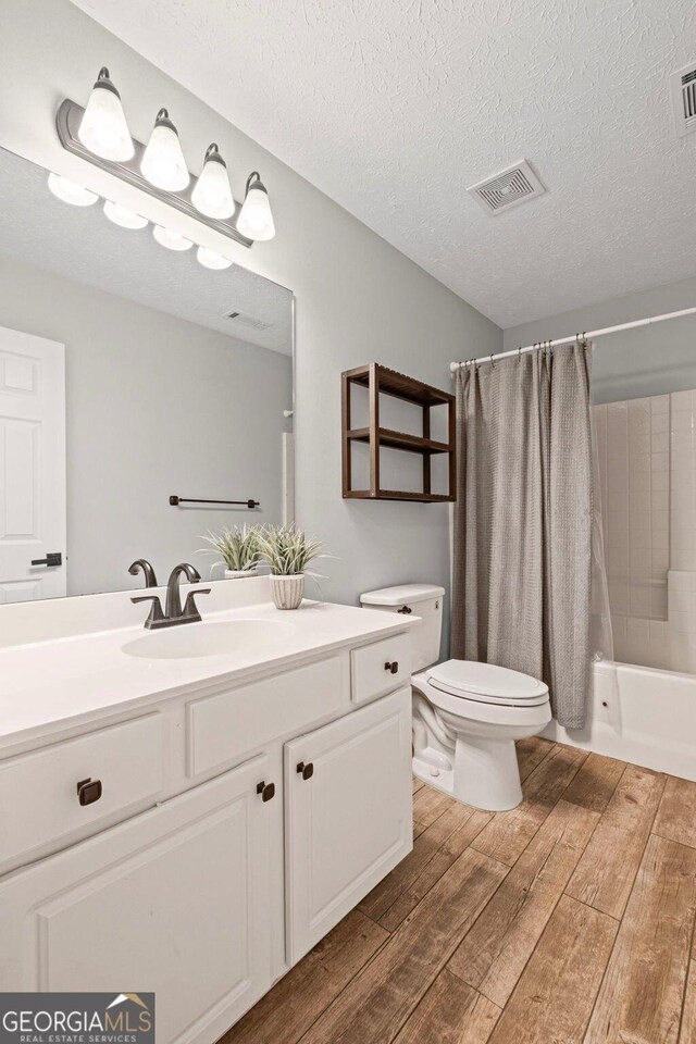 125 Sable Pointe Dr, Milton, GA 30004 - full bathroom with wood finished floors, vanity, toilet, shower / bath combination with curtain, and a textured ceiling