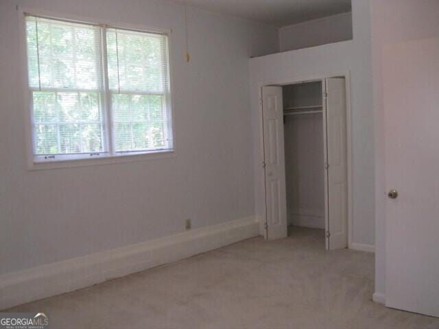 304 Tunis Rd, Mcdonough, GA 30253 - unfurnished bedroom featuring light carpet, multiple windows, baseboards, and a closet