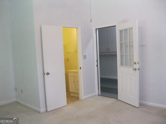 304 Tunis Rd, Mcdonough, GA 30253 - unfurnished bedroom with light colored carpet, baseboards, ensuite bathroom, a walk in closet, and a closet