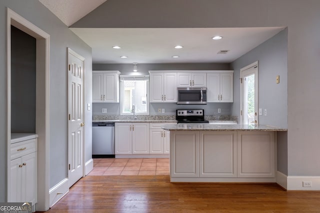 1650 Vintage Club Dr, Greensboro, GA 30642 - kitchen featuring appliances with stainless steel finishes, white cabinetry, light wood-style floors, light stone counters, and recessed lighting