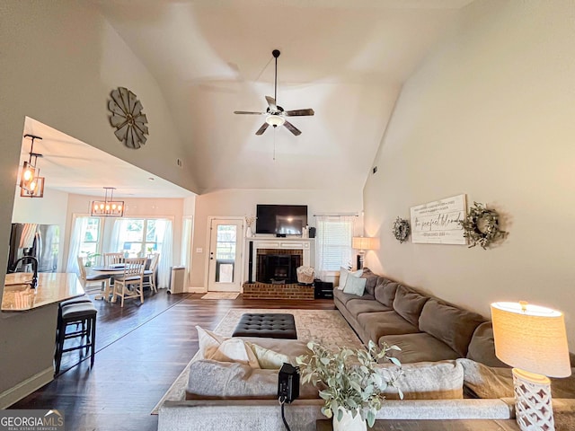 125 Kayla Ct, Locust Grove, GA 30248 - living area featuring dark wood-style floors, a ceiling fan, a brick fireplace, high vaulted ceiling, and baseboards