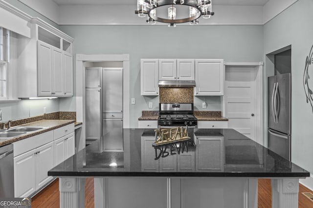 3119 Conyers St SE, Covington, GA 30014 - kitchen featuring stainless steel appliances, under cabinet range hood, white cabinetry, a sink, and dark wood finished floors