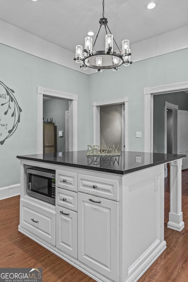 3119 Conyers St SE, Covington, GA 30014 - kitchen featuring stainless steel microwave, a chandelier, a kitchen island, white cabinets, and dark wood-style flooring