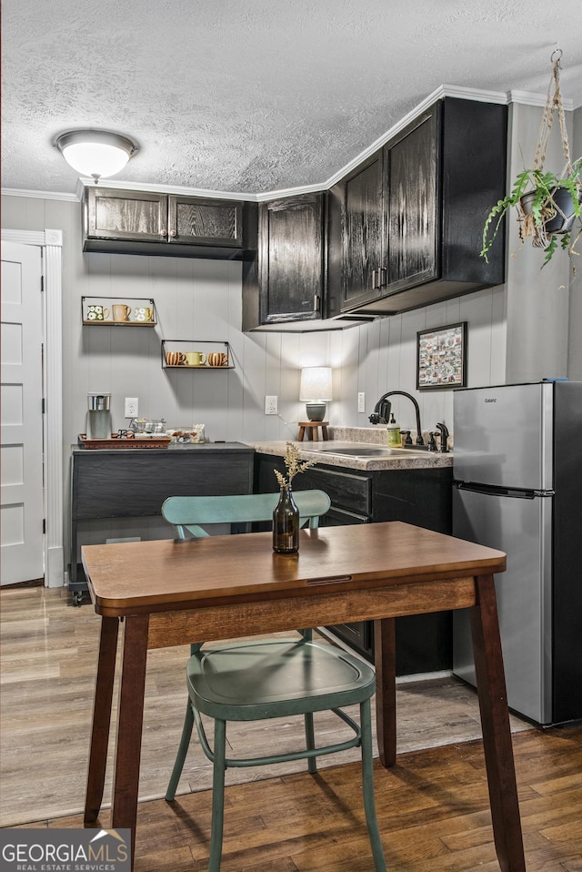 3119 Conyers St SE, Covington, GA 30014 - kitchen with freestanding refrigerator, a textured ceiling, a sink, crown molding, and dark cabinetry