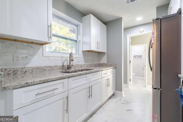 8500 Bowen Ct, Jonesboro, GA 30238 - kitchen featuring freestanding refrigerator, a sink, light marble finish flooring, white cabinets, and decorative backsplash
