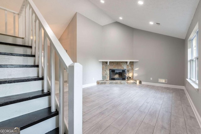 8500 Bowen Ct, Jonesboro, GA 30238 - unfurnished living room featuring lofted ceiling, wood finished floors, a stone fireplace, baseboards, and stairs