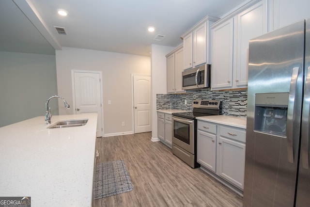26 Sepia Oak Dr, Newnan, GA 30263 - kitchen featuring appliances with stainless steel finishes, a sink, light countertops, decorative backsplash, and light wood finished floors