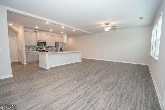 26 Sepia Oak Dr, Newnan, GA 30263 - kitchen with appliances with stainless steel finishes, open floor plan, wood finished floors, ceiling fan, and an island with sink