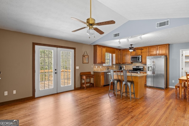 3725 Concord Rd, Newborn, GA 30056 - kitchen featuring stainless steel appliances, ceiling fan, brown cabinetry, light wood-style flooring, and vaulted ceiling