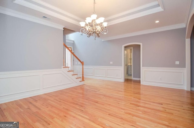 1570 Woodberry Run Dr, Snellville, GA 30078 - spare room with arched walkways, light wood-type flooring, a chandelier, stairway, and a decorative wall