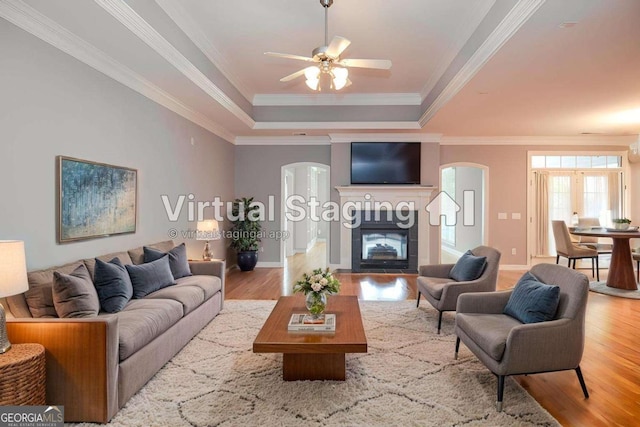 1570 Woodberry Run Dr, Snellville, GA 30078 - living room featuring arched walkways, a tray ceiling, wood finished floors, a ceiling fan, and crown molding
