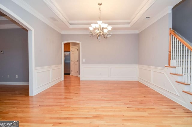 1570 Woodberry Run Dr, Snellville, GA 30078 - unfurnished room featuring arched walkways, light wood finished floors, a chandelier, a tray ceiling, and wainscoting