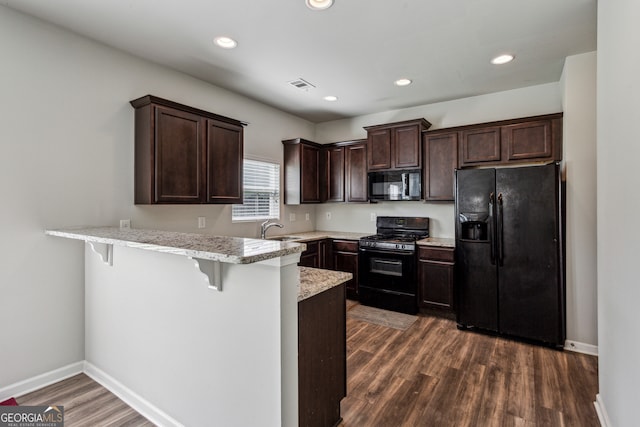 98 Concord Pl, Hiram, GA 30141 - kitchen with black appliances, a peninsula, dark brown cabinets, dark wood-style floors, and a breakfast bar area