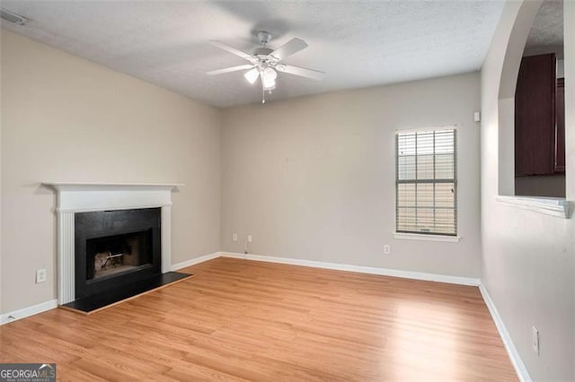 11151 Aliyah Dr, Hampton, GA 30228 - unfurnished living room with light wood finished floors, a ceiling fan, a fireplace, and arched walkways