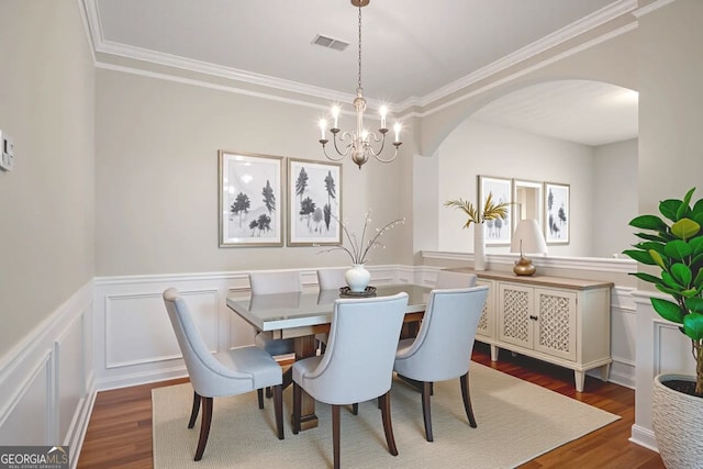 11151 Aliyah Dr, Hampton, GA 30228 - dining space with arched walkways, dark wood-type flooring, a chandelier, ornamental molding, and wainscoting