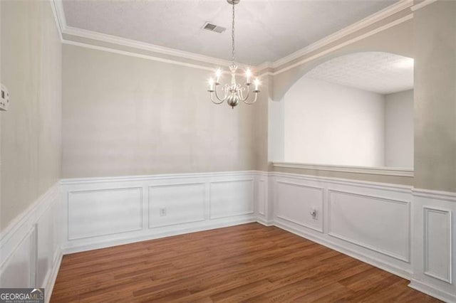 11151 Aliyah Dr, Hampton, GA 30228 - unfurnished dining area with a chandelier, wood finished floors, arched walkways, ornamental molding, and a wainscoted wall