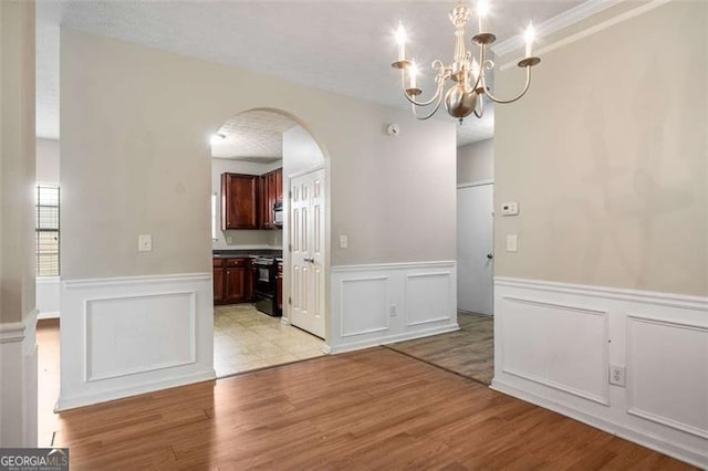 11151 Aliyah Dr, Hampton, GA 30228 - unfurnished dining area featuring arched walkways, a chandelier, a wainscoted wall, light wood-style floors, and a decorative wall