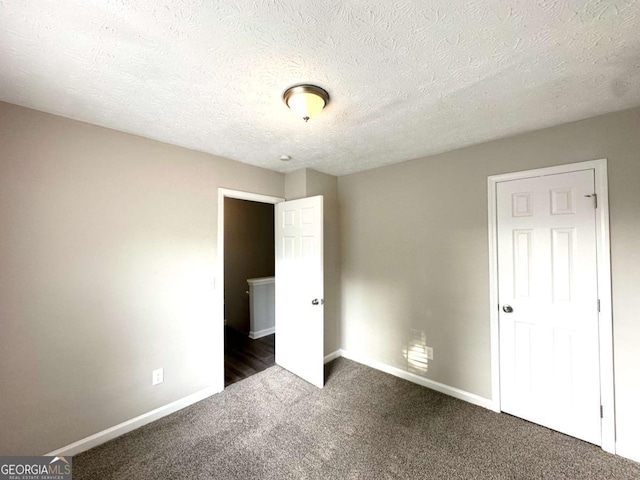 4320 Catalpa Way, Ellenwood, GA 30294 - unfurnished bedroom with dark colored carpet, baseboards, and a textured ceiling