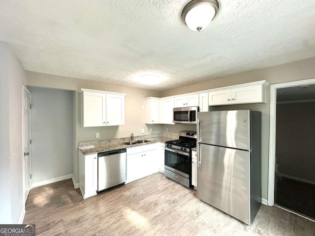 4320 Catalpa Way, Ellenwood, GA 30294 - kitchen with stainless steel appliances, a sink, light wood-type flooring, and a textured ceiling