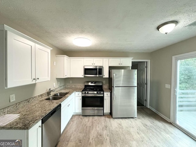 4320 Catalpa Way, Ellenwood, GA 30294 - kitchen with stainless steel appliances, a sink, light wood-style floors, white cabinets, and a textured ceiling