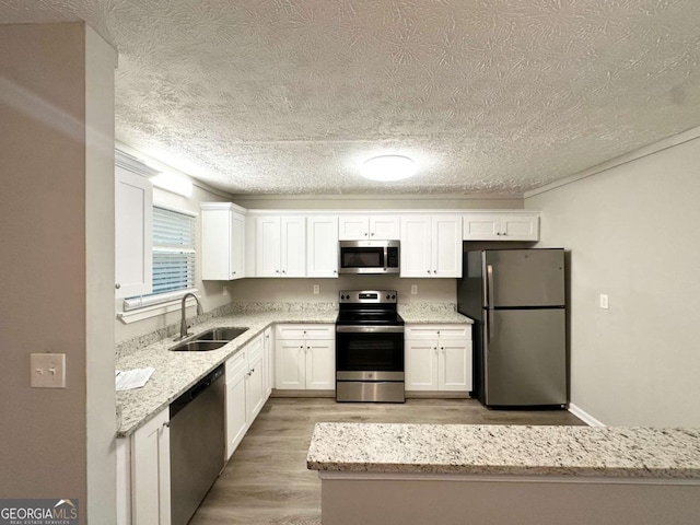 2784 Rockdale Dr, Decatur, GA 30034 - kitchen with stainless steel appliances, a sink, light wood-style floors, white cabinets, and a textured ceiling