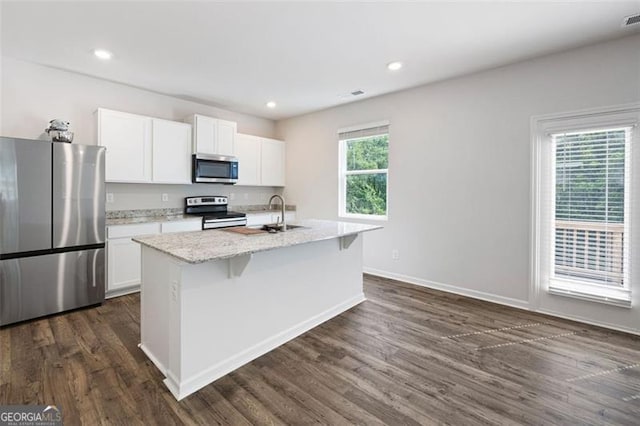 312 Deer Run Dr, Dallas, GA 30132 - kitchen featuring stainless steel appliances, white cabinetry, dark wood-type flooring, light stone counters, and a center island with sink