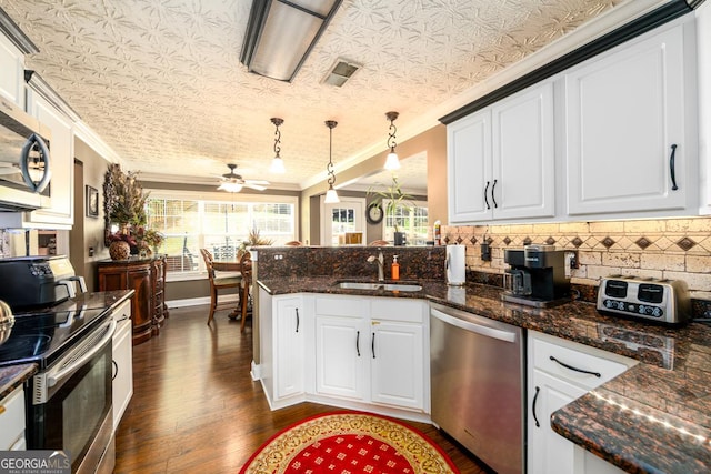 7282 Litany Ct, Flowery Branch, GA 30542 - kitchen with appliances with stainless steel finishes, a peninsula, ornamental molding, dark wood-style floors, and backsplash