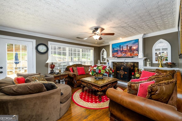 7282 Litany Ct, Flowery Branch, GA 30542 - living room featuring wood finished floors, ceiling fan, crown molding, and a premium fireplace