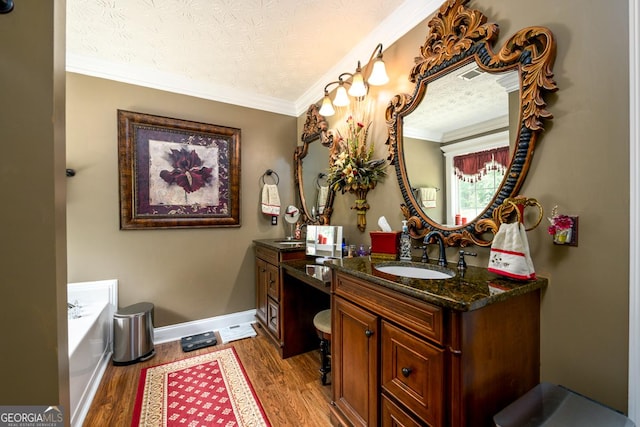 7282 Litany Ct, Flowery Branch, GA 30542 - bathroom featuring vanity, wood finished floors, ornamental molding, a garden tub, and a textured ceiling