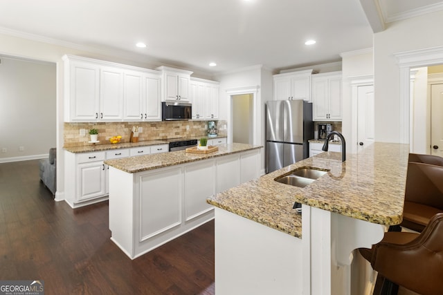 152 Jackson Dr, Forsyth, GA 31029 - kitchen with stainless steel appliances, a kitchen island with sink, a sink, dark wood-style floors, and crown molding