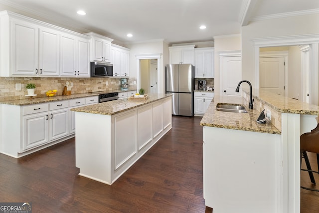 152 Jackson Dr, Forsyth, GA 31029 - kitchen featuring an island with sink, stainless steel appliances, crown molding, a sink, and dark wood-style floors