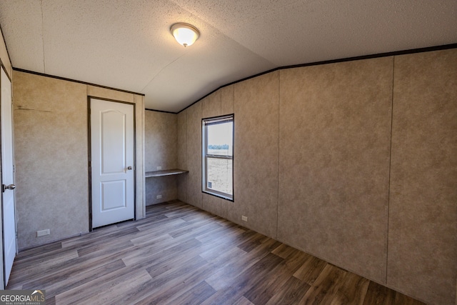 461 Mccord Rd, East Dublin, GA 31027 - unfurnished bedroom with wood finished floors, vaulted ceiling, and a textured ceiling