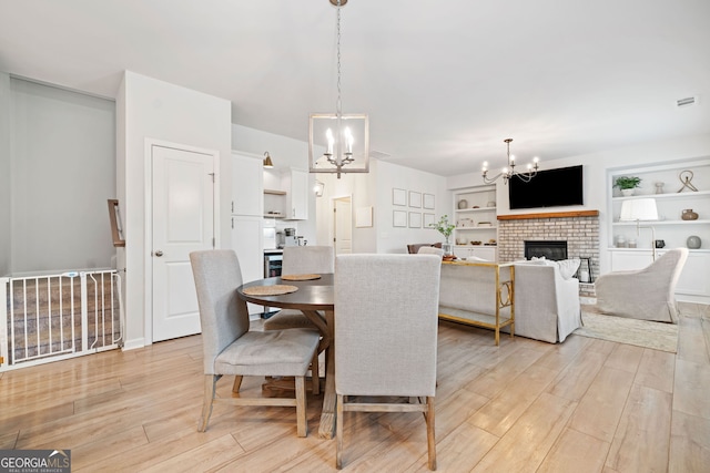 306 Coppergate Ct, Holly Springs, GA 30115 - dining area with a chandelier, light wood finished floors, and a brick fireplace