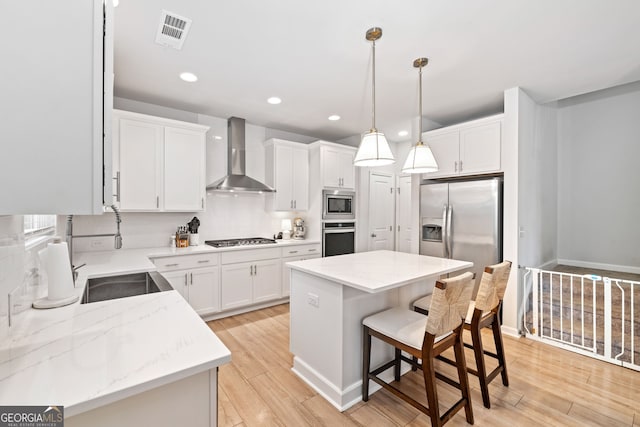 306 Coppergate Ct, Holly Springs, GA 30115 - kitchen featuring wall chimney exhaust hood, stainless steel appliances, recessed lighting, a breakfast bar, and light wood-style flooring