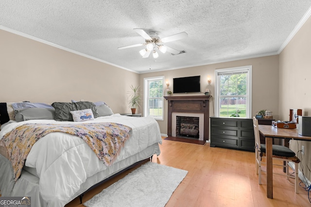1072 Burtons Ferry Highway, Sylvania, GA 30467 - bedroom featuring light wood-style flooring, crown molding, a textured ceiling, a fireplace, and a ceiling fan
