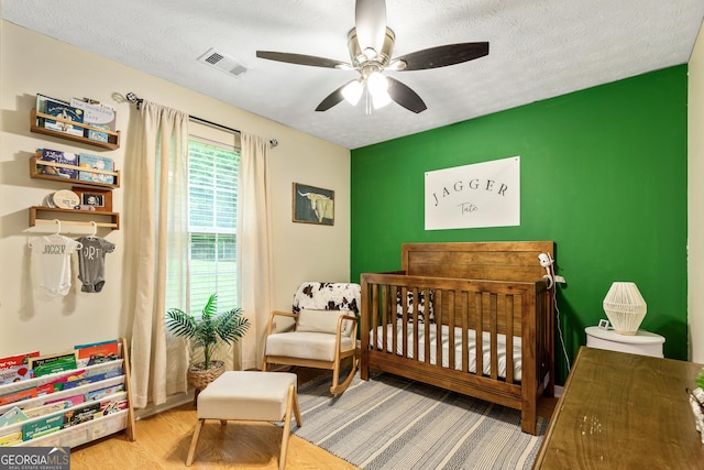 460 Old Tree Dr, Jackson, GA 30233 - bedroom featuring a nursery area, wood finished floors, ceiling fan, and a textured ceiling