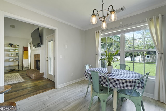 510 Braves Field Dr, Guyton, GA 31312 - dining space with baseboards, crown molding, light wood-style flooring, a fireplace, and a chandelier