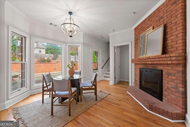 2903 Ashebrooke Dr NE, Marietta, GA 30068 - dining room with a chandelier, stairs, a brick fireplace, crown molding, and light wood-style flooring