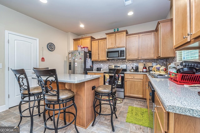 874 Crescent Ln Unit 52, Griffin, GA 30224 - kitchen with appliances with stainless steel finishes, a center island, a breakfast bar, tasteful backsplash, and light stone counters
