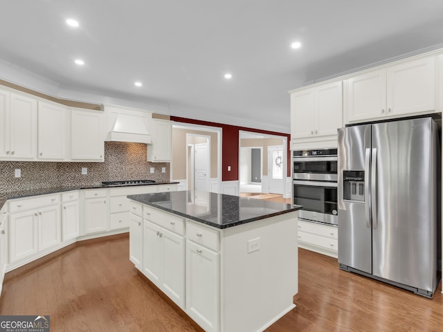 302 Burberry Ct, Griffin, GA 30223 - kitchen with appliances with stainless steel finishes, wall chimney exhaust hood, a center island, white cabinetry, and wood finished floors