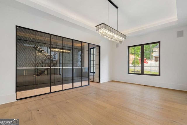 245 Traditions Dr, Alpharetta, GA 30004 - empty room featuring wood finished floors, a chandelier, and a tray ceiling