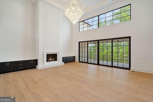 245 Traditions Dr, Alpharetta, GA 30004 - unfurnished living room with a chandelier, a high ceiling, light wood-style flooring, and plenty of natural light