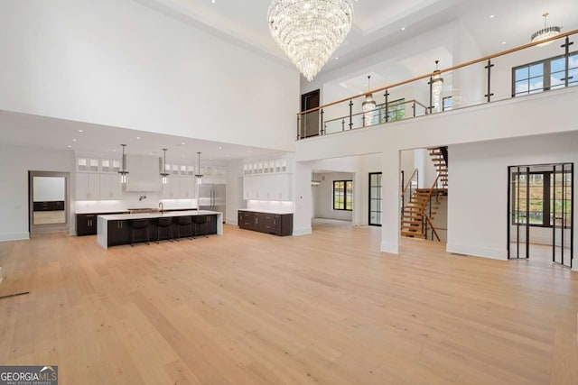 245 Traditions Dr, Alpharetta, GA 30004 - unfurnished living room with a high ceiling, a chandelier, light wood-style flooring, stairs, and recessed lighting
