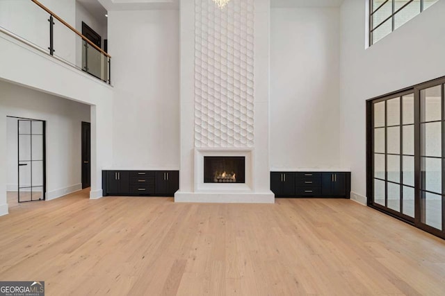 245 Traditions Dr, Alpharetta, GA 30004 - unfurnished living room with a high ceiling, light wood finished floors, and a large fireplace