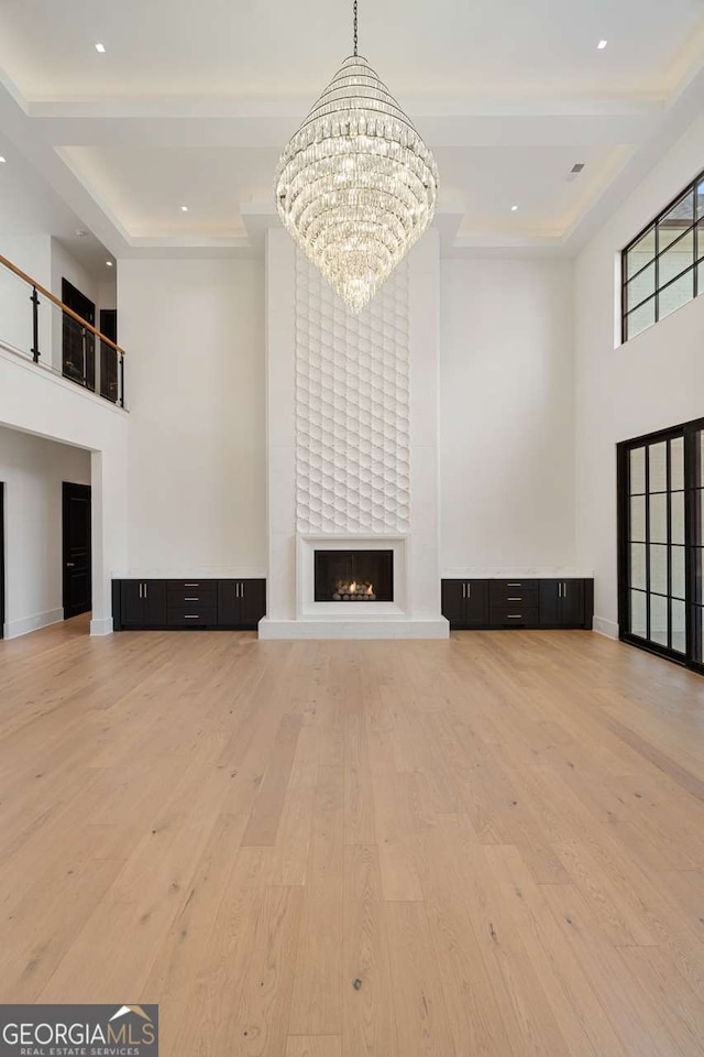 245 Traditions Dr, Alpharetta, GA 30004 - unfurnished living room with a high ceiling, hardwood / wood-style flooring, a chandelier, a large fireplace, and recessed lighting