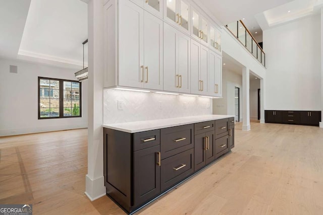 245 Traditions Dr, Alpharetta, GA 30004 - kitchen with white cabinetry, light wood-style floors, light countertops, decorative backsplash, and glass insert cabinets