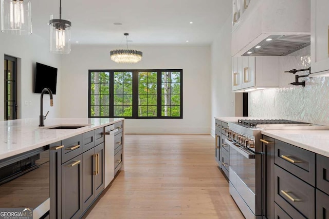 245 Traditions Dr, Alpharetta, GA 30004 - kitchen featuring stainless steel stove, custom exhaust hood, light wood-style floors, decorative light fixtures, and backsplash