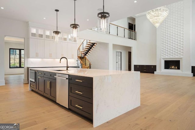 245 Traditions Dr, Alpharetta, GA 30004 - kitchen with stainless steel dishwasher, a chandelier, white cabinetry, light wood finished floors, and a high ceiling